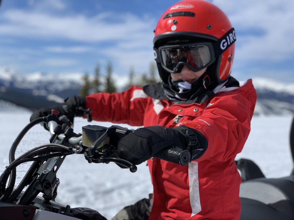 Young rider in a red helmet on a touring snowmobile near the Continental Divide above Winter Park